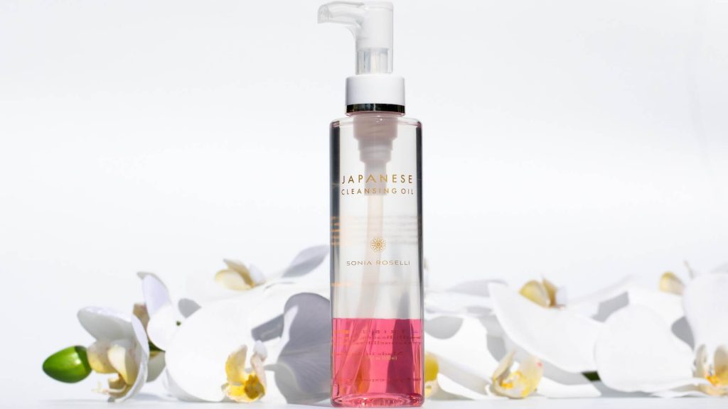 A cleansing oil with some flowers behind